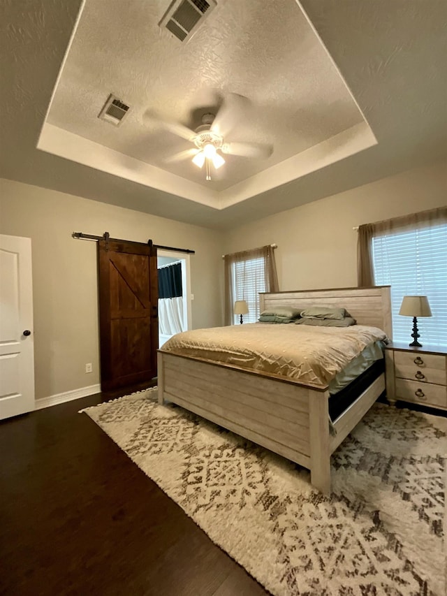 bedroom with a tray ceiling, visible vents, and baseboards