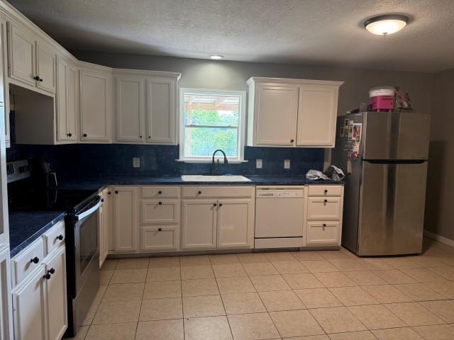 1445 Bahama Dr, Vidor, TX 77662 - kitchen with appliances with stainless steel finishes, tasteful backsplash, dark countertops, white cabinets, and a textured ceiling