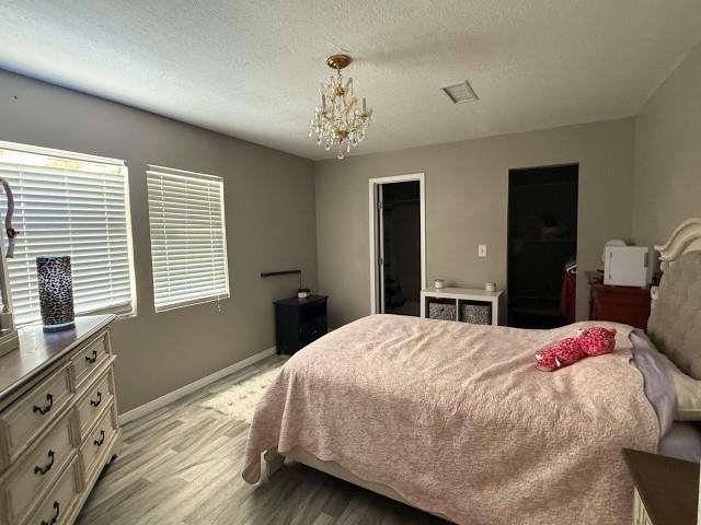 1445 Bahama Dr, Vidor, TX 77662 - bedroom featuring light wood-style floors, a chandelier, a spacious closet, a closet, and a textured ceiling
