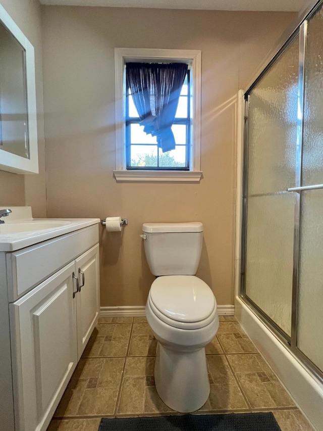 full bath featuring a stall shower, toilet, vanity, and baseboards