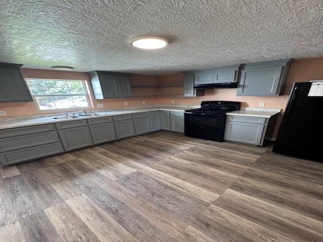 kitchen with gray cabinetry, black appliances, sink, light hardwood / wood-style flooring, and a textured ceiling