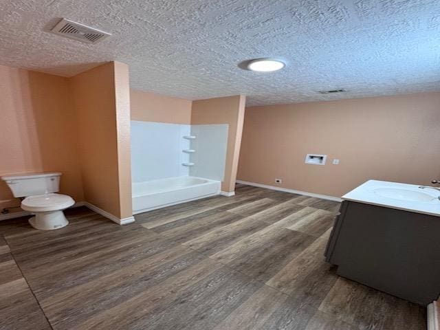 bathroom with vanity, a textured ceiling, a shower, wood-type flooring, and toilet