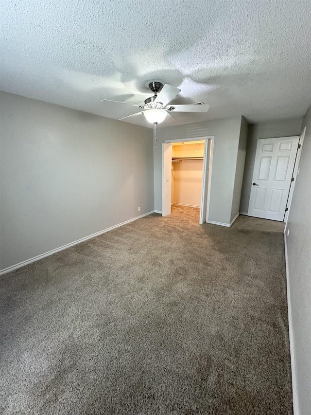 unfurnished bedroom with ceiling fan, carpet floors, a closet, a textured ceiling, and a walk in closet