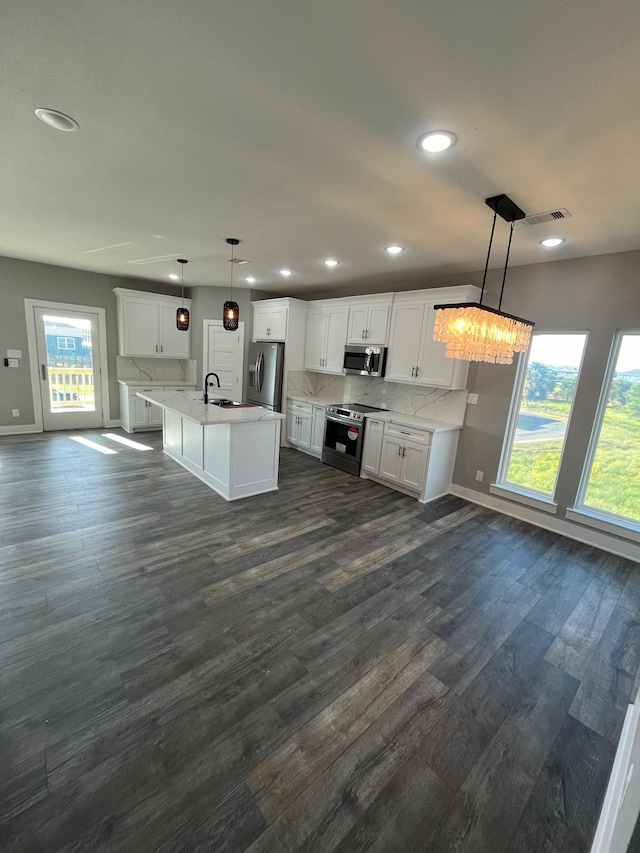 kitchen featuring white cabinets, appliances with stainless steel finishes, decorative light fixtures, and a healthy amount of sunlight