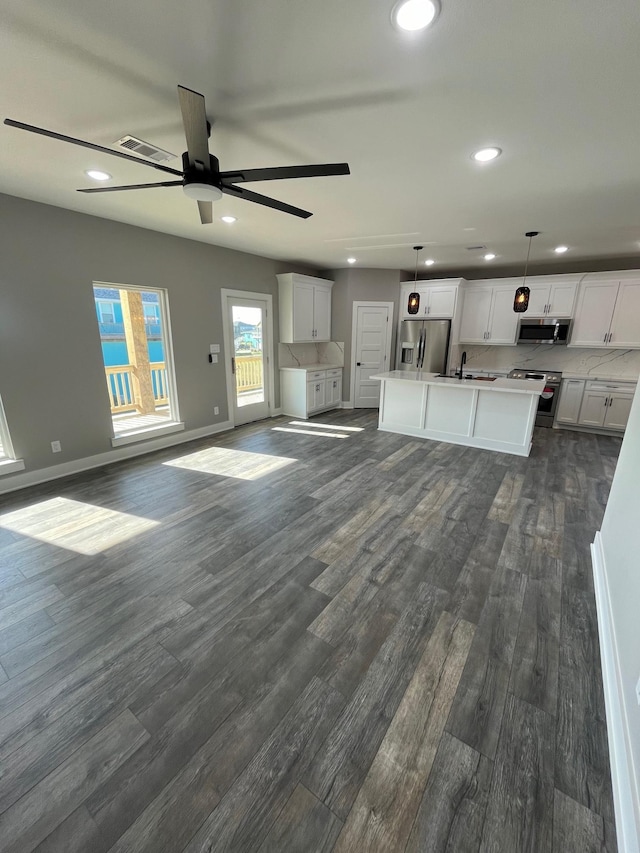 kitchen featuring a center island, stainless steel appliances, white cabinetry, and hanging light fixtures