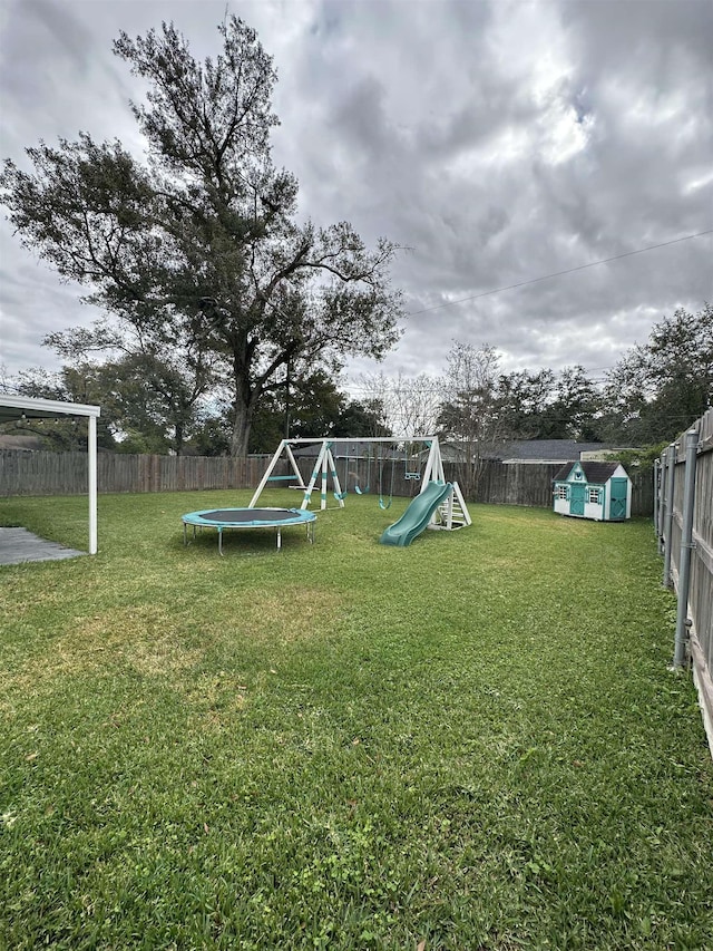 view of yard with a playground, a storage unit, and a trampoline