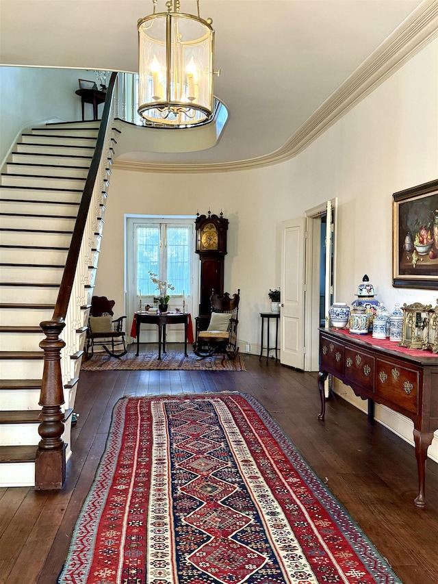 foyer with dark hardwood / wood-style floors, ornamental molding, and a chandelier