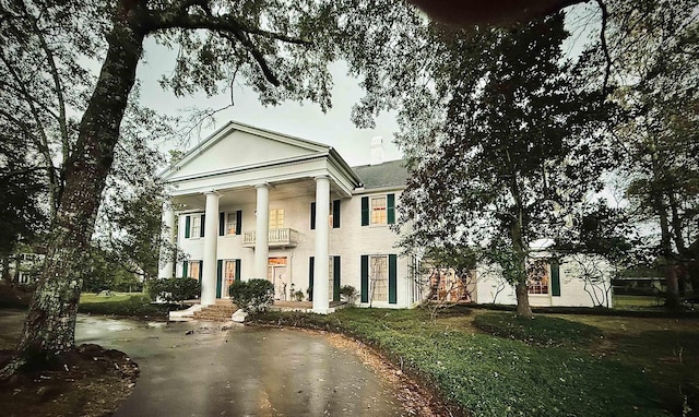 neoclassical home featuring a balcony and a front yard