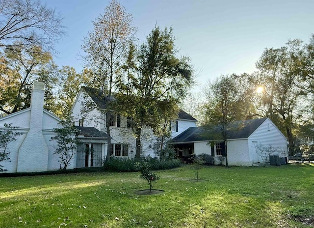 rear view of property featuring a lawn and central air condition unit