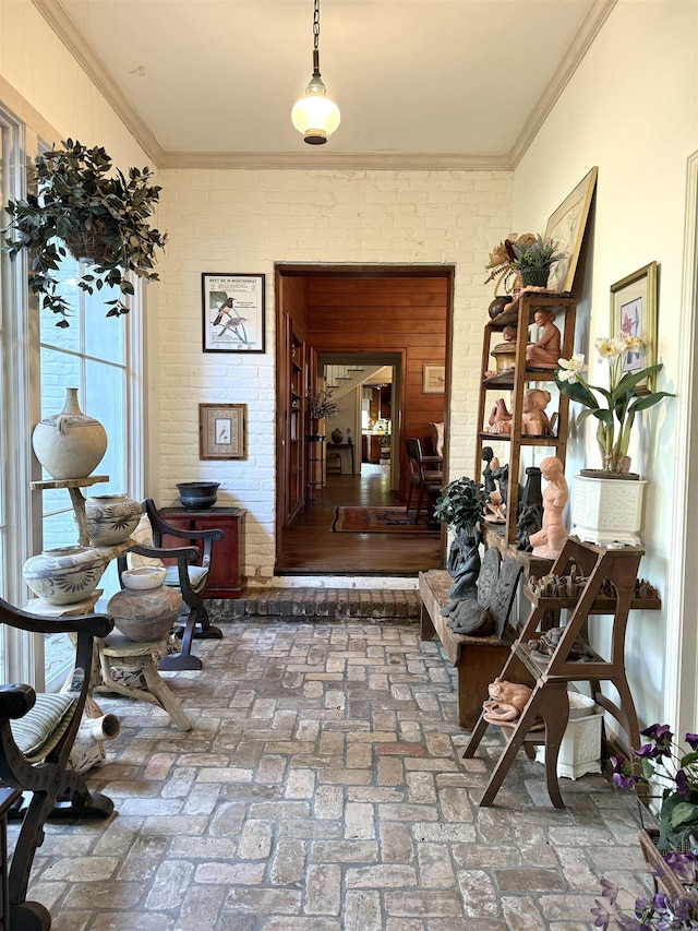 hallway featuring crown molding and brick wall