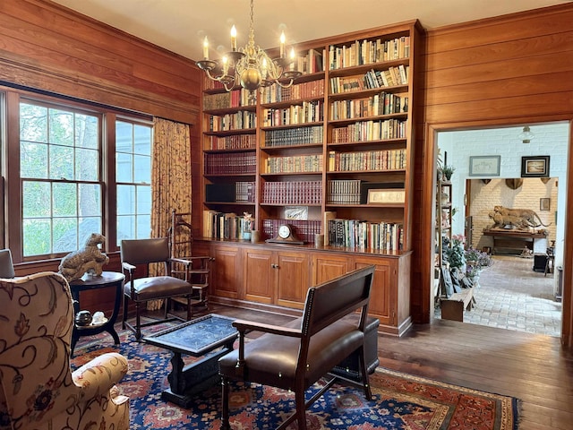 living area featuring wood walls, dark wood-type flooring, and a notable chandelier