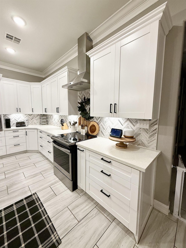 kitchen featuring white cabinetry, backsplash, ornamental molding, electric range, and wall chimney range hood