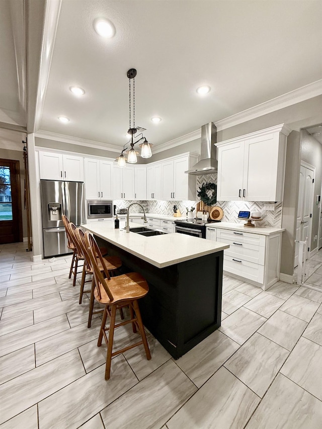 kitchen with wall chimney exhaust hood, sink, an island with sink, stainless steel appliances, and white cabinets