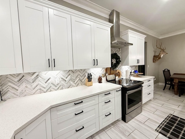 kitchen with white cabinetry, backsplash, electric range, crown molding, and wall chimney range hood