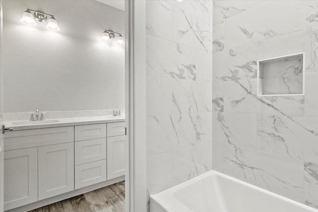 bathroom featuring vanity, wood-type flooring, and tiled shower / bath