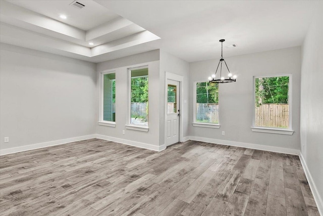 interior space featuring a raised ceiling, light hardwood / wood-style flooring, and an inviting chandelier