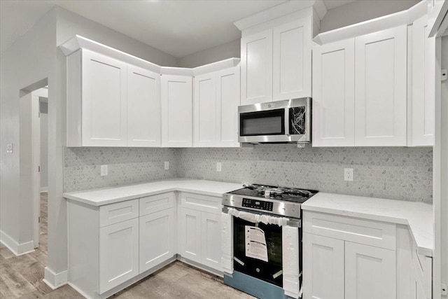 kitchen featuring white cabinetry, backsplash, appliances with stainless steel finishes, and light hardwood / wood-style flooring