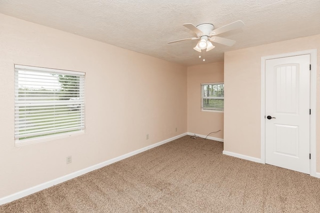 spare room featuring baseboards, light carpet, a ceiling fan, and a wealth of natural light