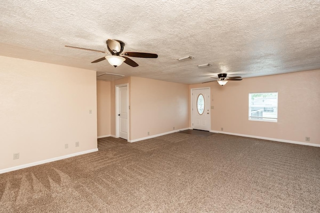 unfurnished living room featuring ceiling fan, a textured ceiling, carpet, attic access, and baseboards