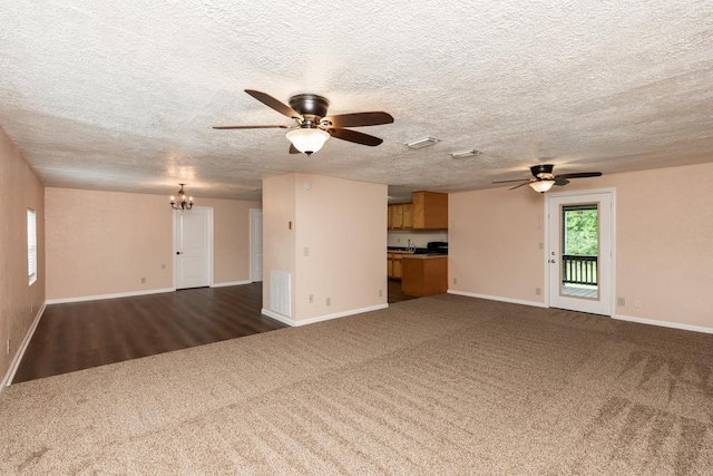 unfurnished living room with visible vents, dark carpet, baseboards, a textured ceiling, and ceiling fan with notable chandelier