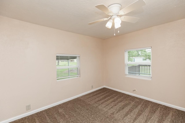 unfurnished room featuring a ceiling fan, baseboards, and dark carpet