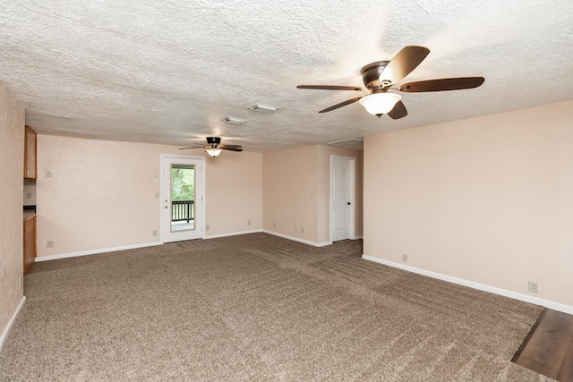 carpeted spare room with baseboards, a ceiling fan, attic access, and a textured ceiling
