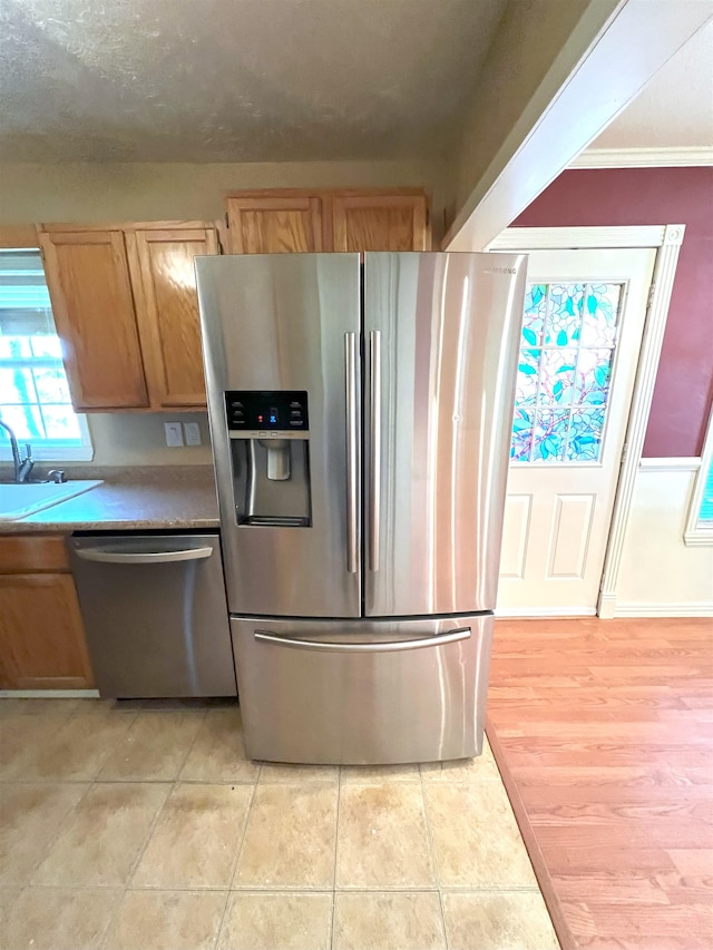 kitchen with crown molding, sink, light tile patterned floors, and stainless steel appliances