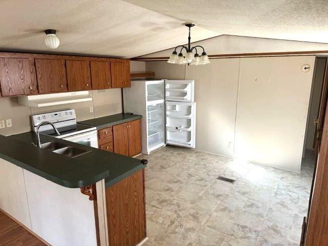 kitchen with sink, exhaust hood, a chandelier, hanging light fixtures, and lofted ceiling