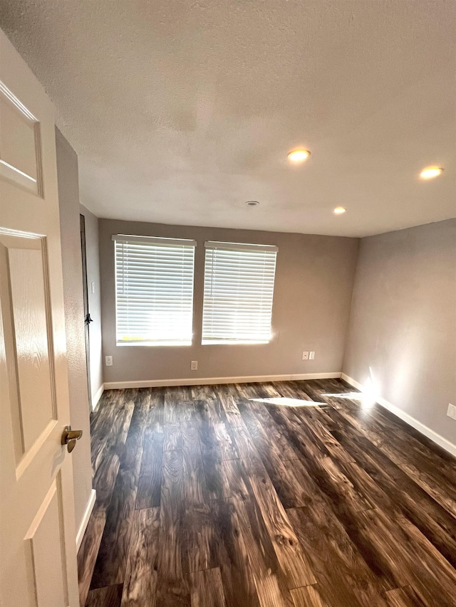 empty room with a textured ceiling and dark hardwood / wood-style floors