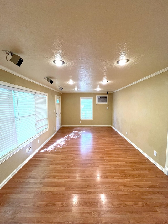 unfurnished room with a wall mounted AC, crown molding, light hardwood / wood-style flooring, and a textured ceiling