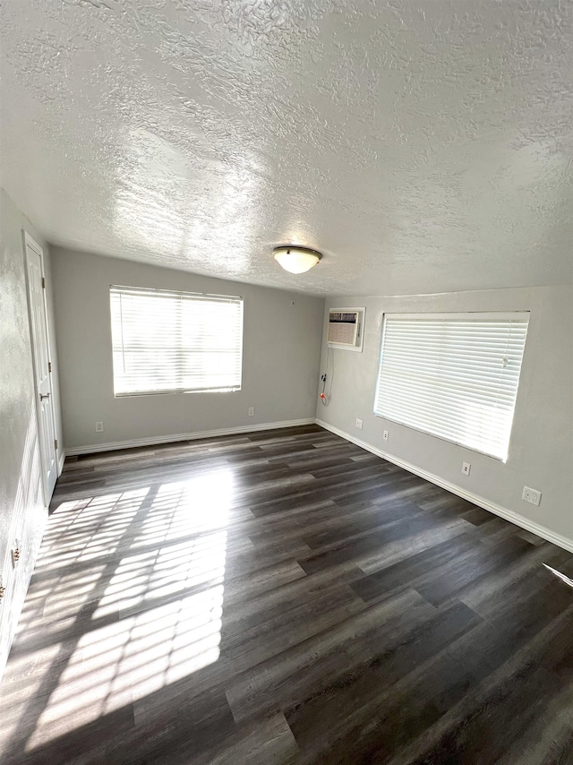 spare room featuring an AC wall unit and dark wood-type flooring