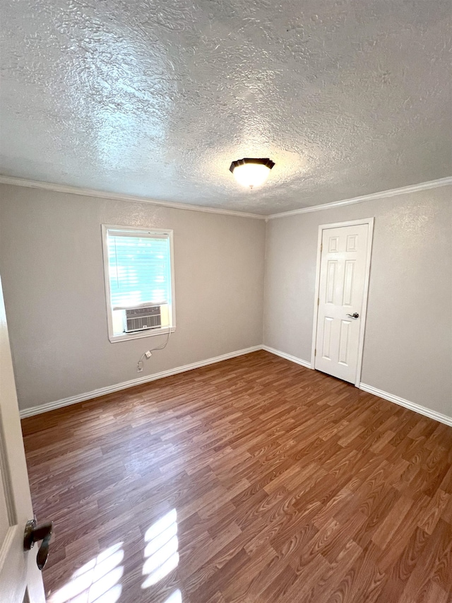 empty room with hardwood / wood-style flooring, cooling unit, ornamental molding, and a textured ceiling