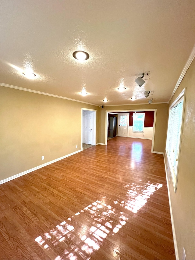 unfurnished room featuring wood-type flooring, a textured ceiling, and ornamental molding