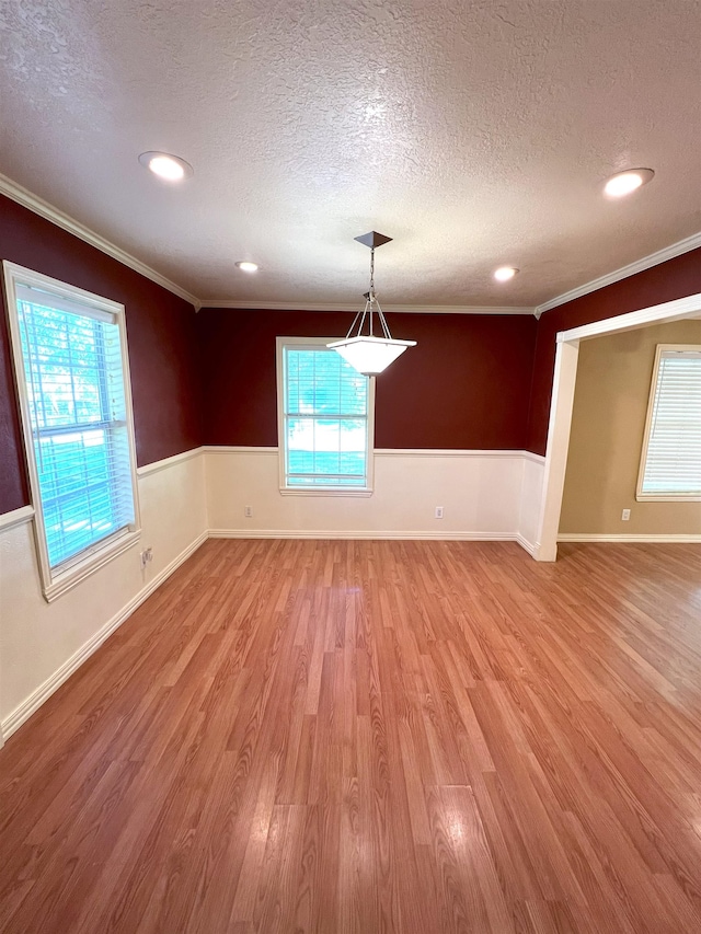 unfurnished dining area featuring crown molding, a textured ceiling, and light hardwood / wood-style flooring