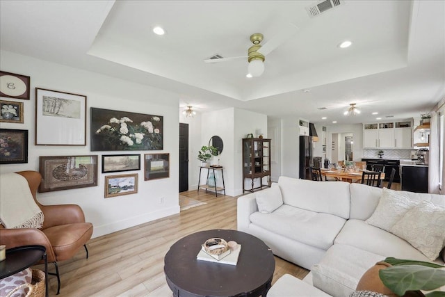 11109 County Road 701, Buna, TX 77612 - living room featuring a tray ceiling, ceiling fan, baseboards, recessed lighting, and light wood-style flooring