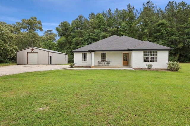 11109 County Road 701, Buna, TX 77612 - view of front of house featuring a front yard, an outdoor structure, a detached garage, gravel driveway, and brick siding
