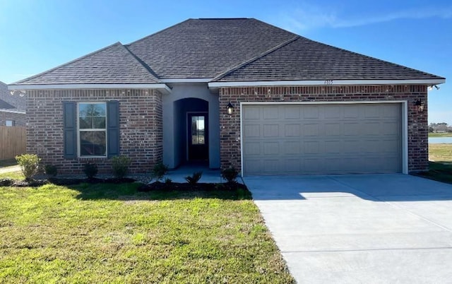 view of front of house with a front yard, driveway, roof with shingles, an attached garage, and brick siding