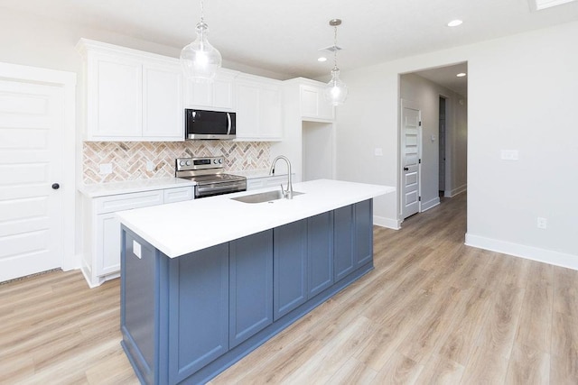 kitchen featuring pendant lighting, stainless steel appliances, a center island with sink, and sink