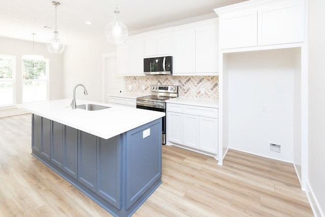 kitchen featuring appliances with stainless steel finishes, a kitchen island with sink, sink, white cabinetry, and hanging light fixtures