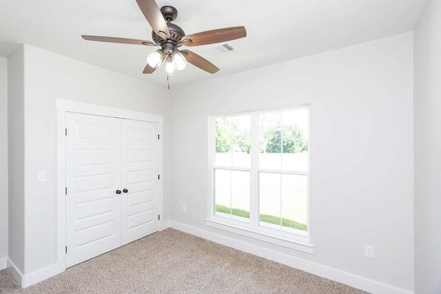 unfurnished bedroom with ceiling fan, multiple windows, light carpet, and a closet