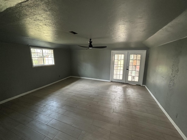 spare room with french doors, vaulted ceiling, ceiling fan, wood-type flooring, and a textured ceiling