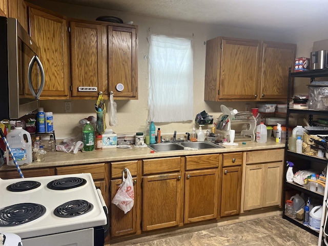 kitchen featuring brown cabinets, stainless steel microwave, light countertops, and a sink