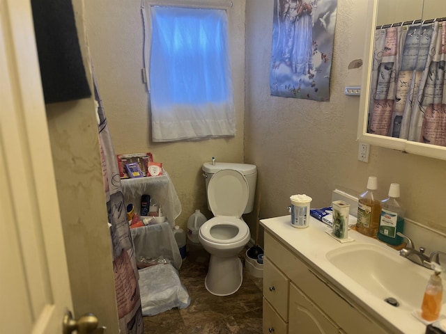 bathroom with a textured wall, vanity, and toilet