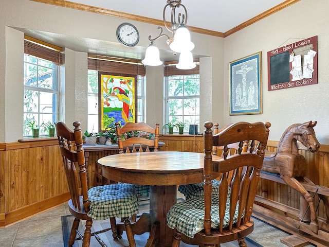 dining room with wood walls, crown molding, a wealth of natural light, and a chandelier