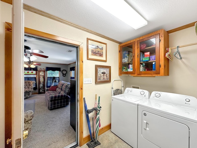 washroom with washing machine and clothes dryer, cabinets, a textured ceiling, and ornamental molding