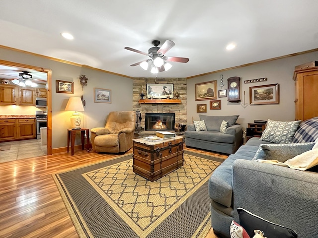 living room with a fireplace, light hardwood / wood-style floors, ceiling fan, and crown molding