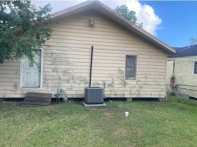 view of side of home with a yard and central AC