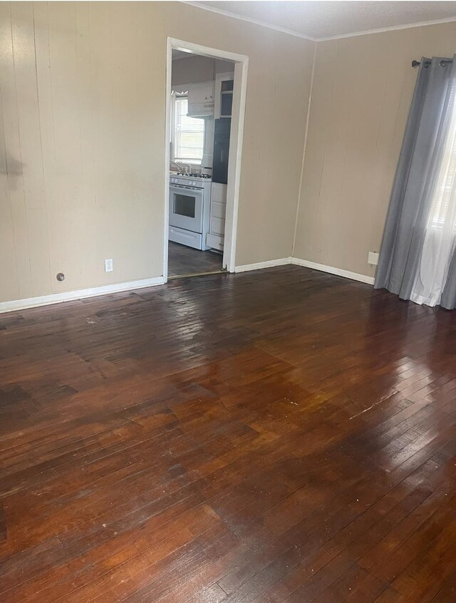 spare room with crown molding and dark wood-type flooring