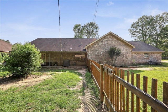 132 County Road 760, Buna, TX 77612 - back of property with brick siding, fence, central AC unit, and a lawn
