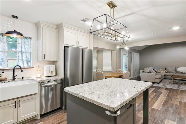 kitchen featuring decorative light fixtures, stainless steel appliances, white cabinets, and a kitchen island